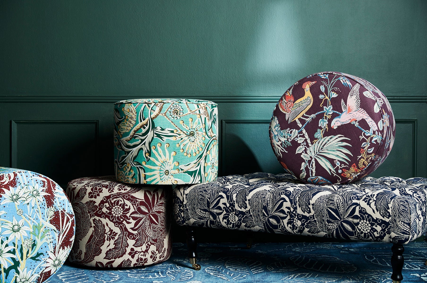 Utopia Goods Classic Buttoned Ottoman: collection of round and cylindrical ottomans in botanical printed fabrics on blue rug