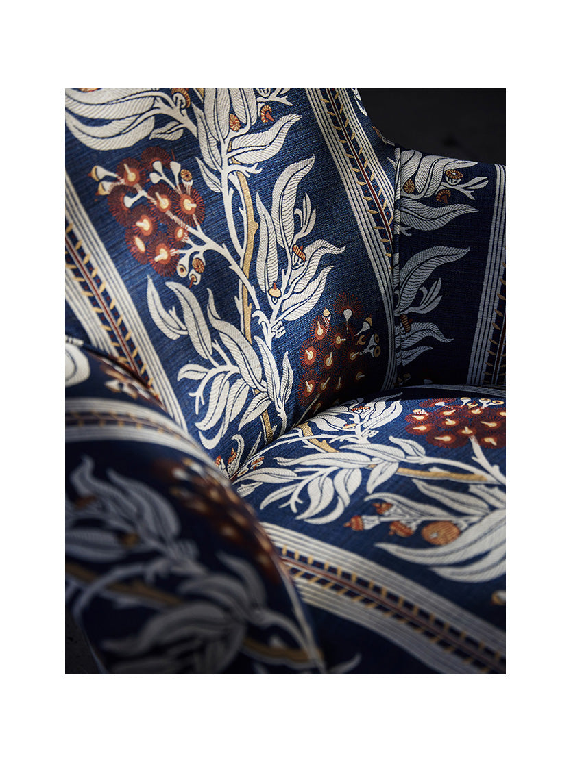 Utopia Goods: close-up of upholstered chair with navy blue fabric featuring white botanical leaves and red floral pattern
