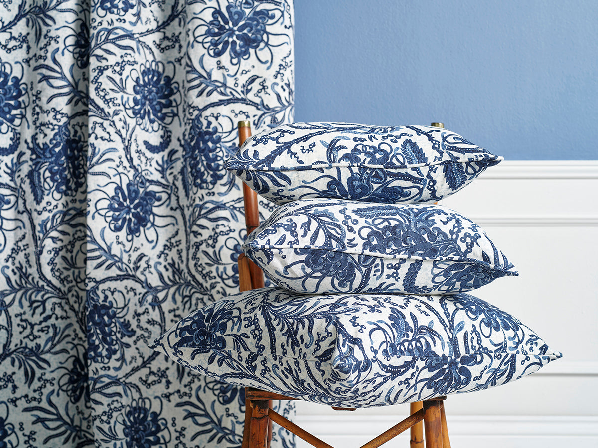 Utopia Goods: three blue and white floral patterned pillows stacked on wooden chair with matching curtain fabric
