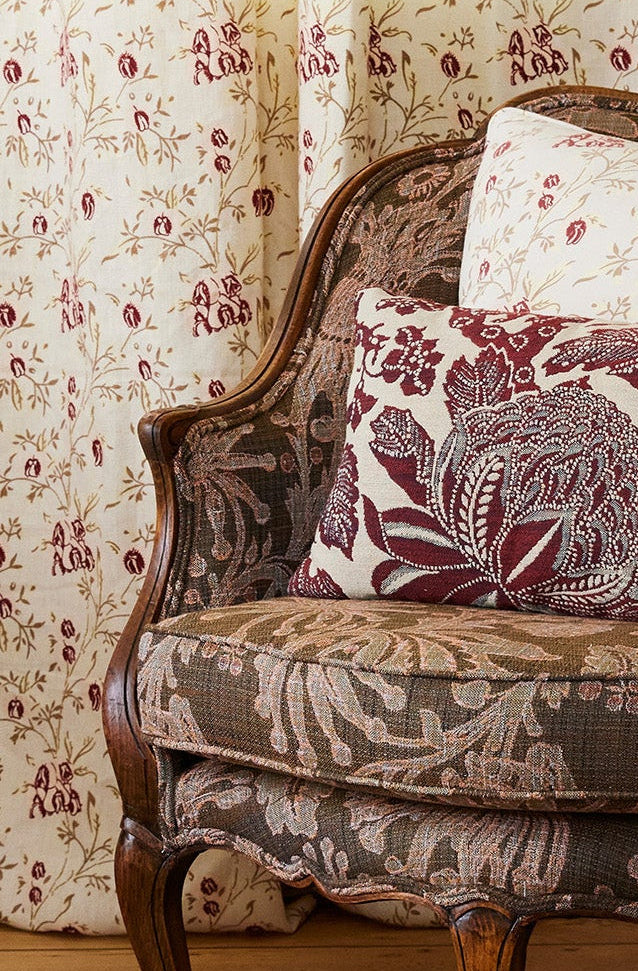Utopia Goods Antique French Bergere Armchair - Firewheel Rust Performance Fabric: ornate wooden chair with botanical print upholstery and red floral cushions in traditional interior setting