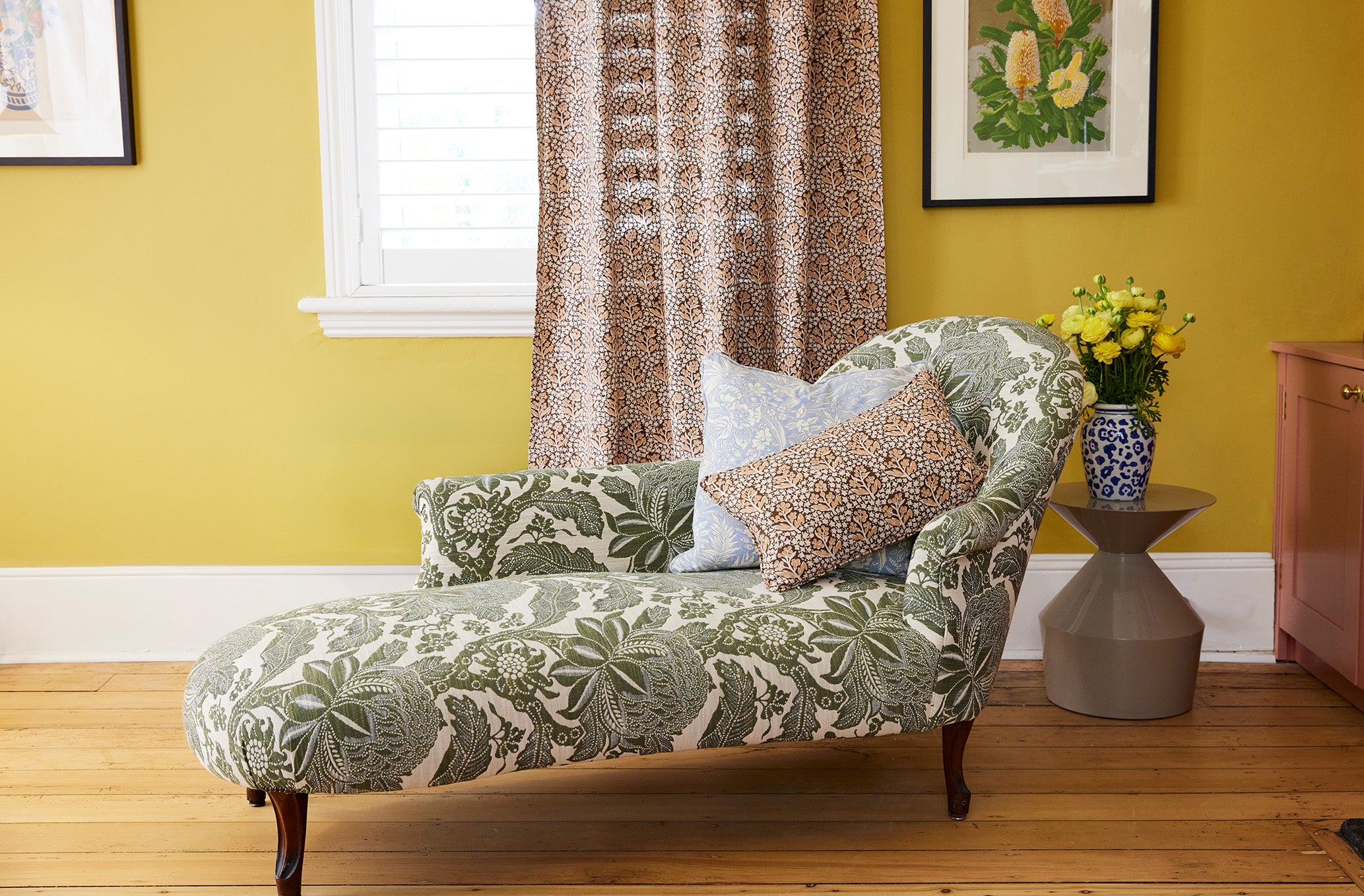 Utopia Goods: chaise lounge with green botanical print in yellow room with leopard curtains and decorative pillows
