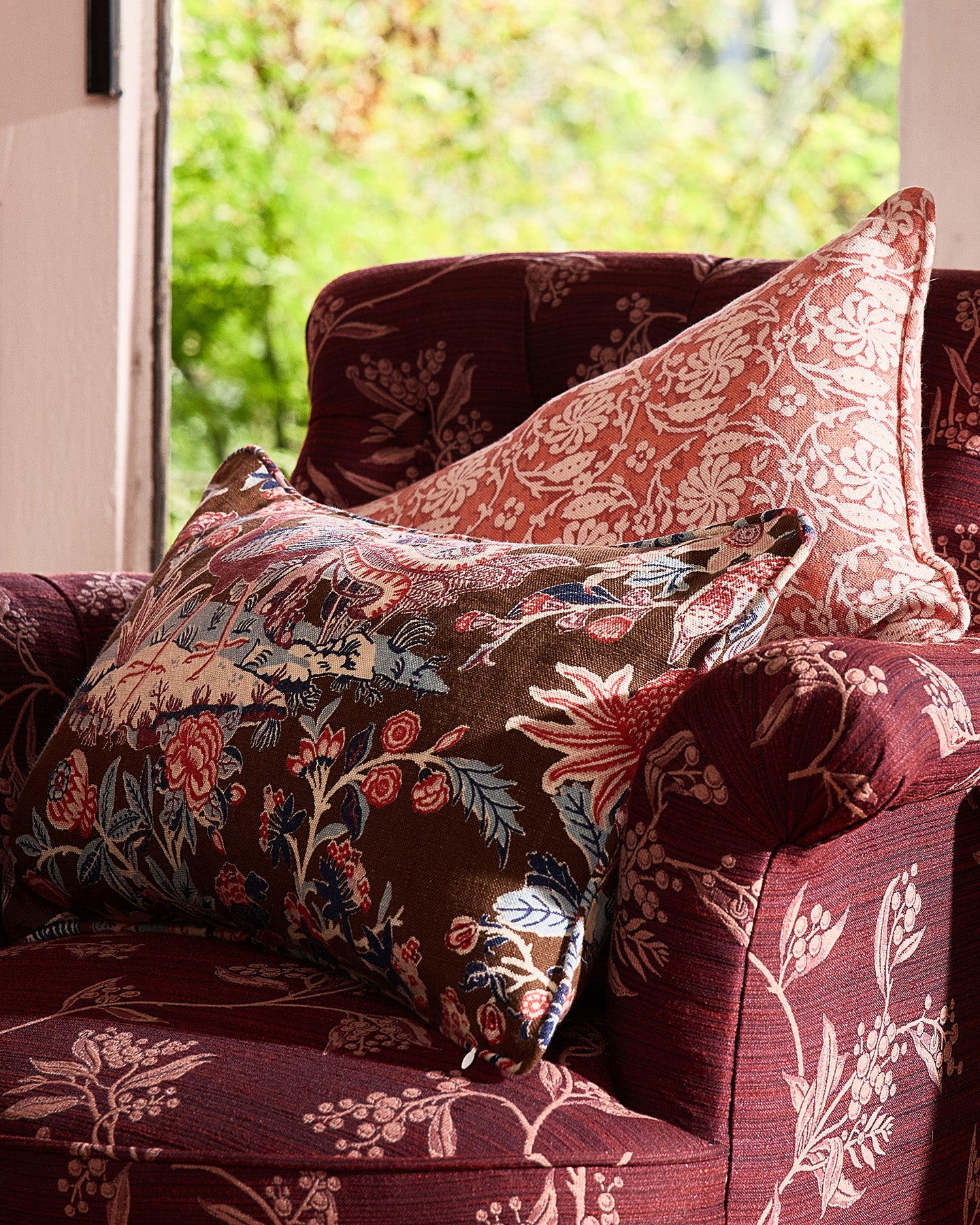 Utopia Goods Arcadia Mocha Bolster Cushion Cover: floral patterned cushions in burgundy tones on upholstered chair by window