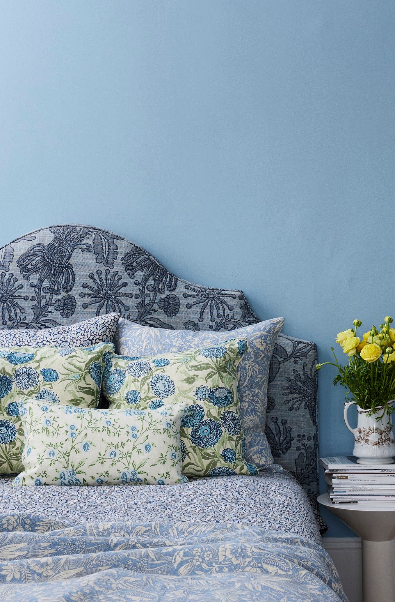 Utopia Goods Everlasting Blue Medium Cushion Cover Unpiped: blue floral linen cushion on bed with matching bedding, blue wall