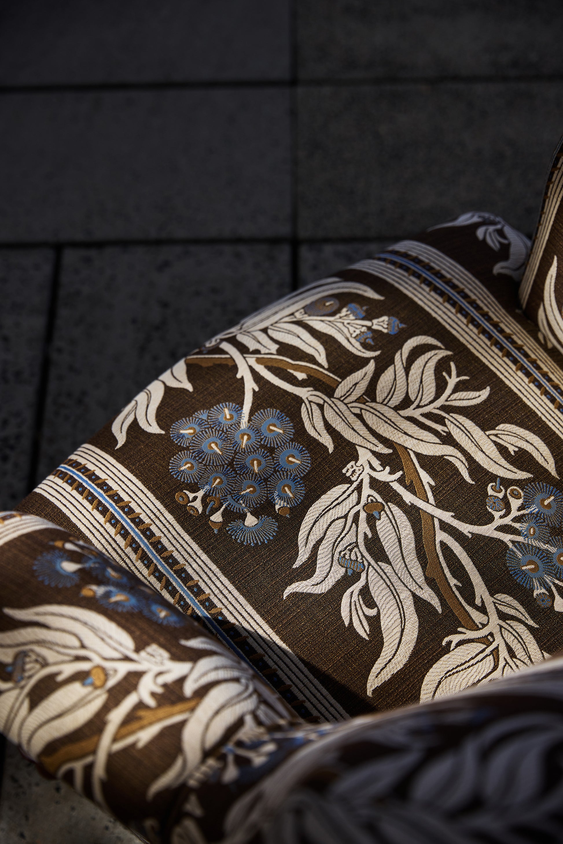 Utopia Goods: close-up of brown fabric with cream floral pattern and blue accents draped over dark surface