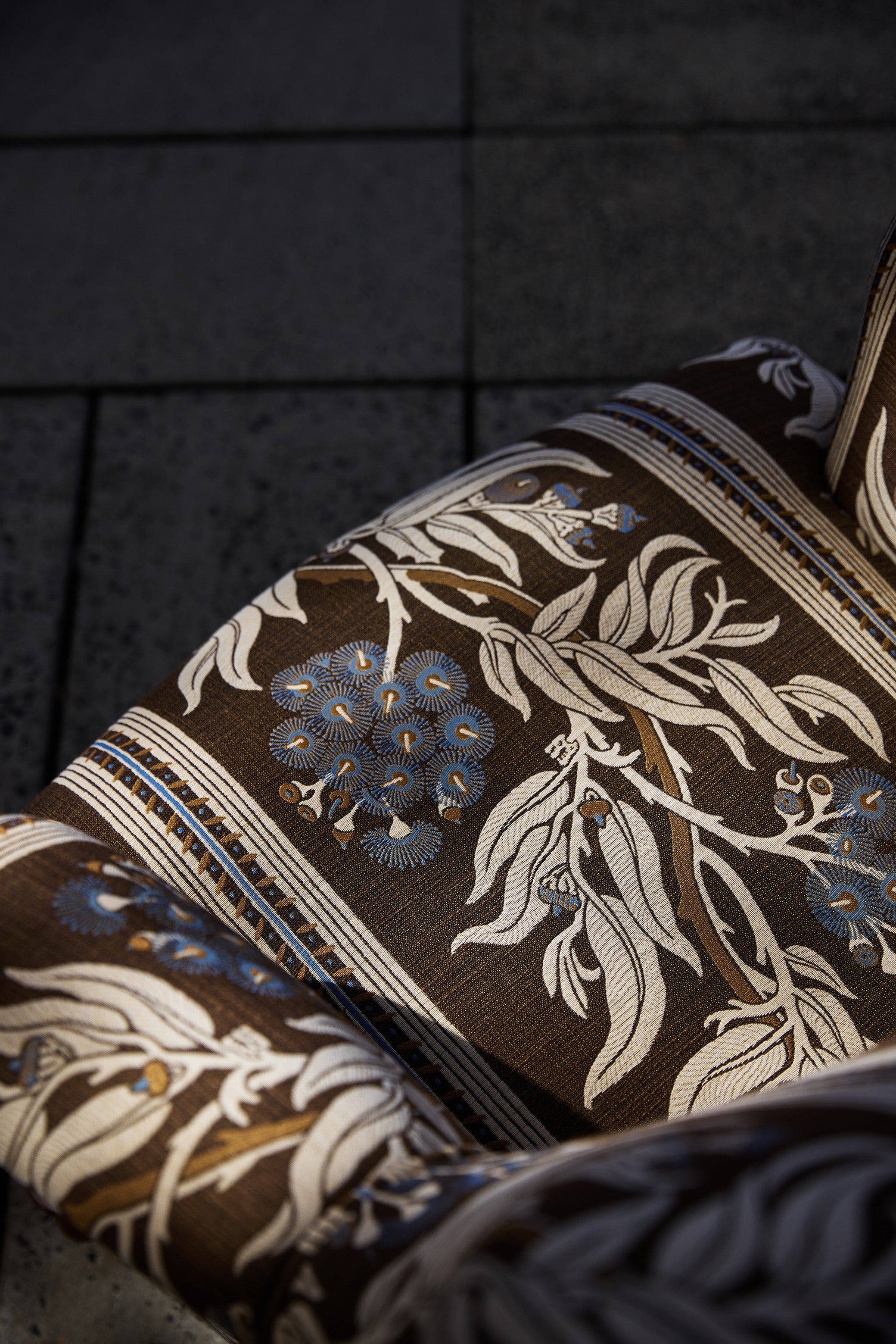 Utopia Goods: close-up of brown fabric with cream floral pattern and blue accents draped over dark surface