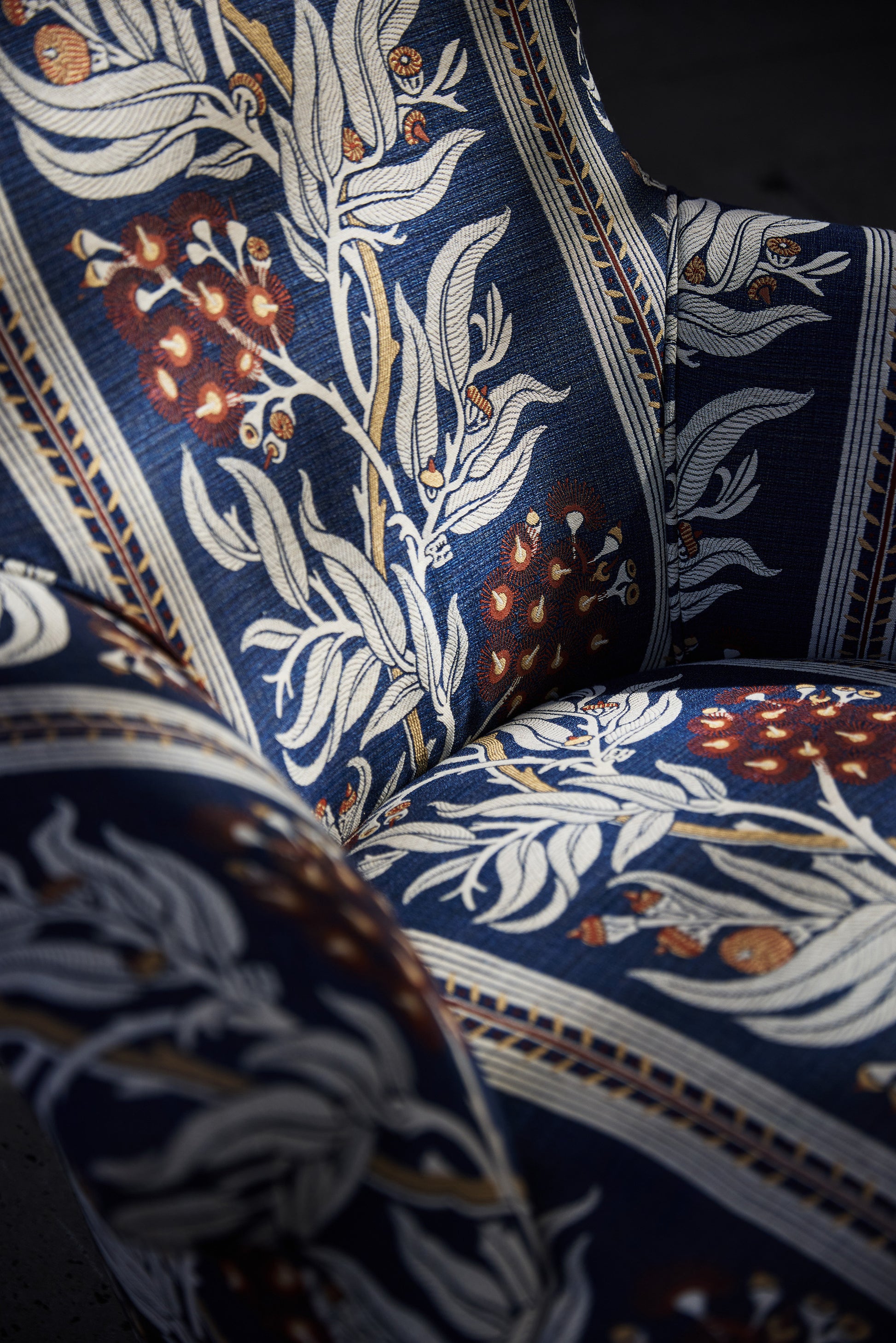 Utopia Goods: close-up of ornate blue fabric with white floral pattern on upholstered chair, showing detailed textile design