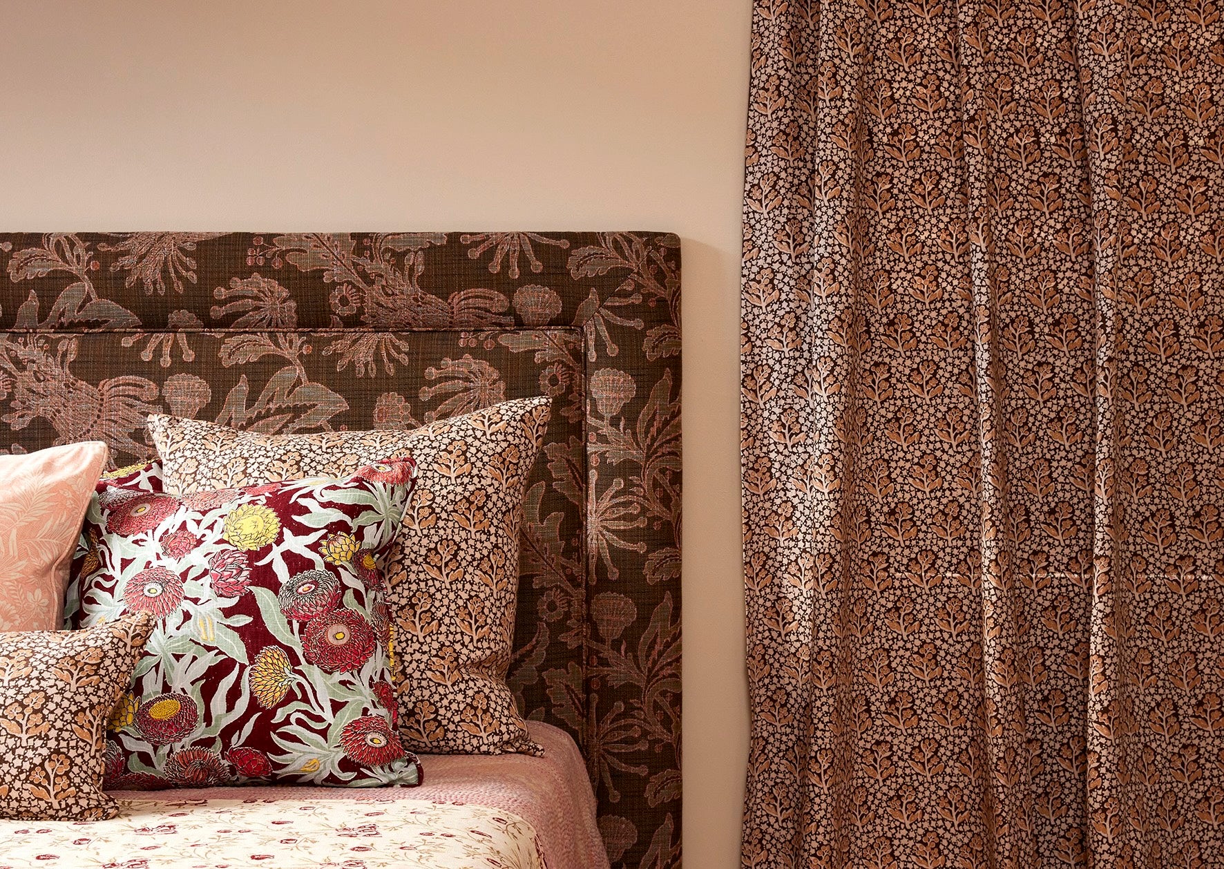 Utopia Goods: bedroom with patterned brown headboard, floral pillows, and matching wallpaper in warm earth tones