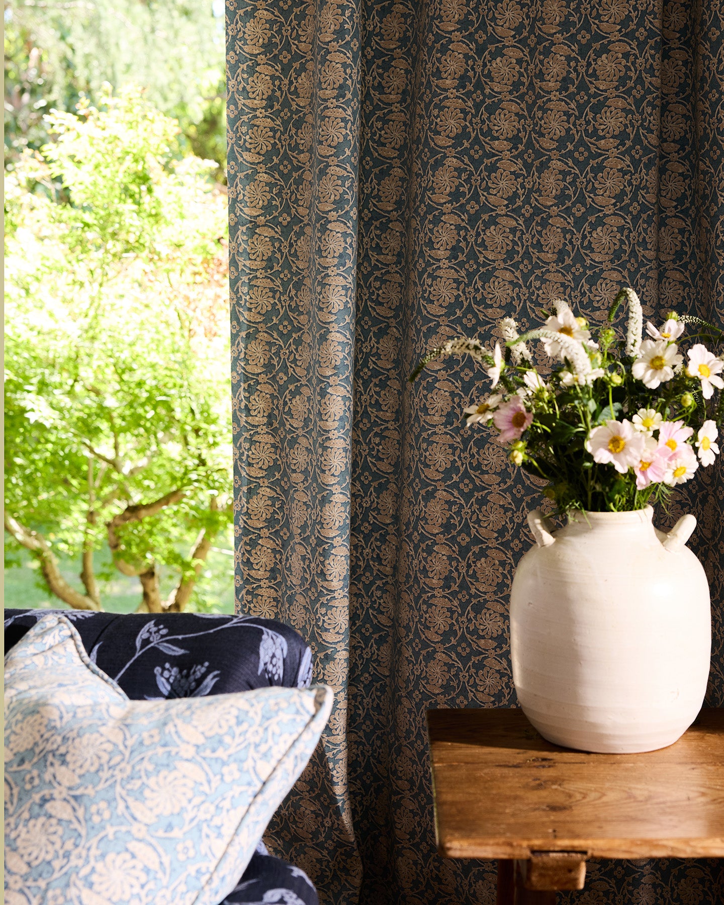 Utopia Goods Pinwheel Ocean Furnishing Linen: navy curtains with golden floral pattern beside chair and flower vase by window