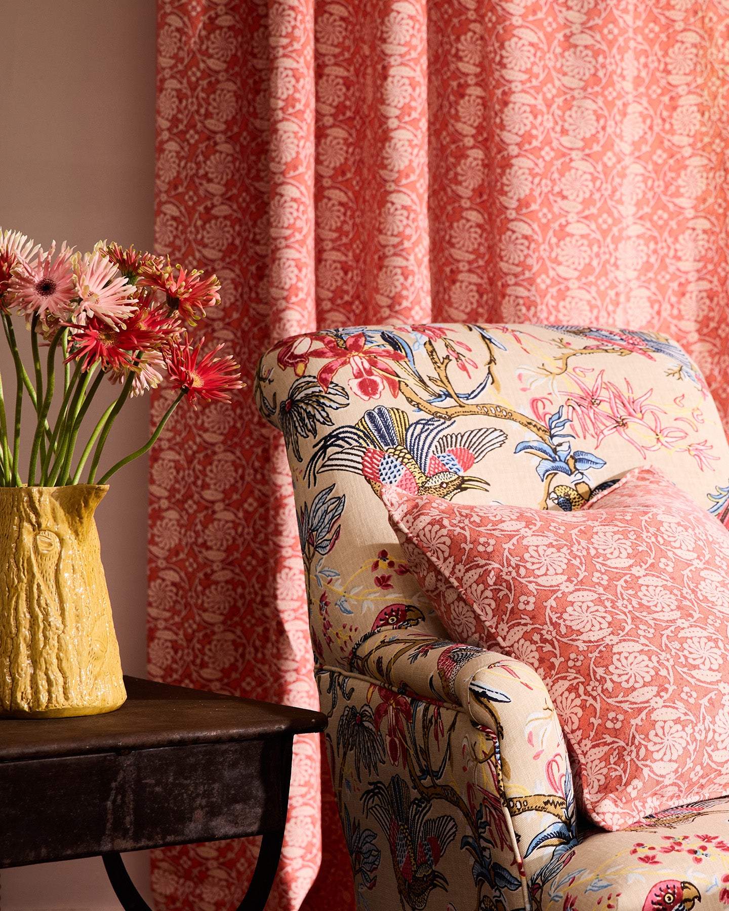Utopia Goods Pinwheel Coral Medium Cushion Cover: coral patterned cushion on floral upholstered chair with matching curtains
