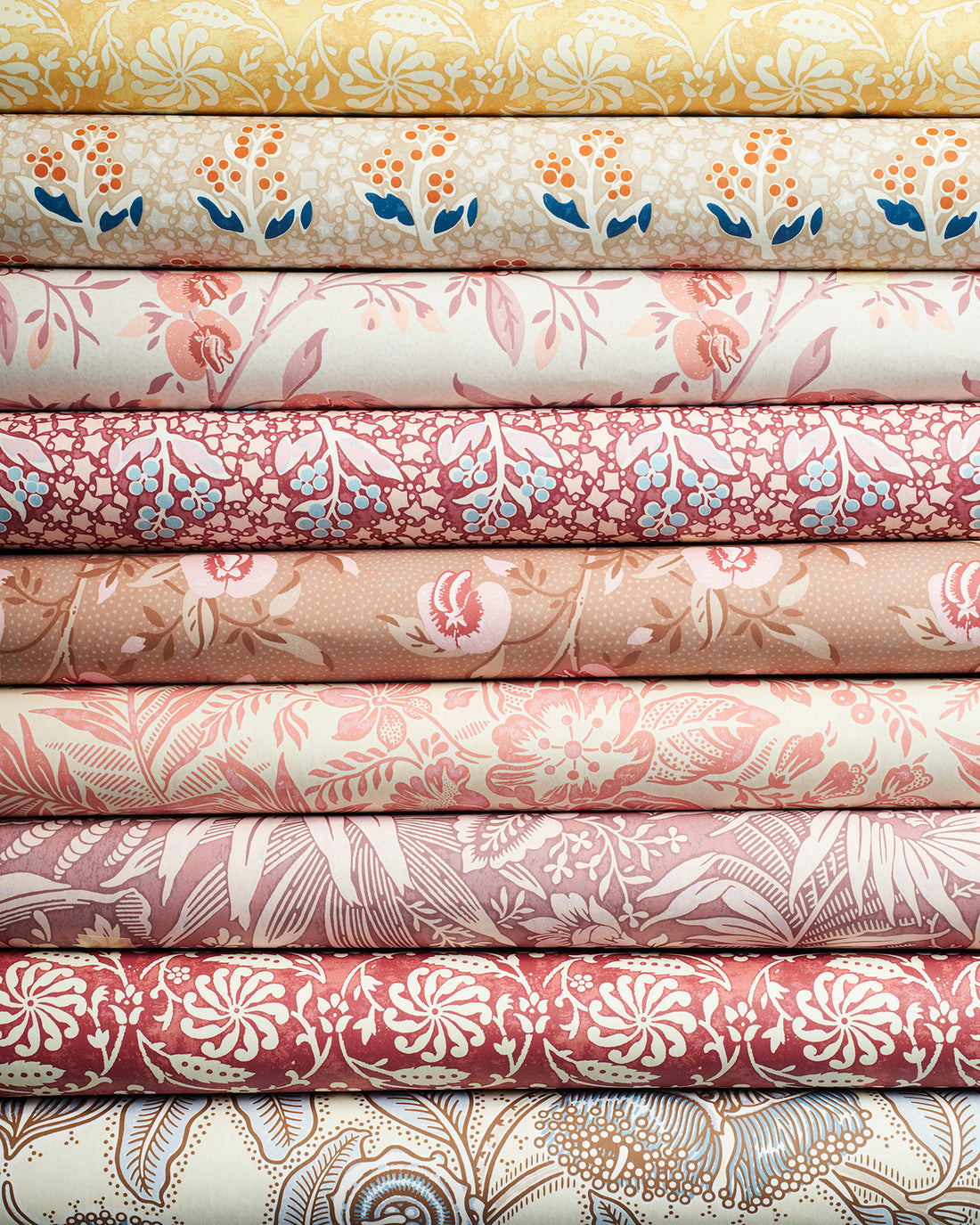 A stack of colourful floral botanical wallpaper rolls