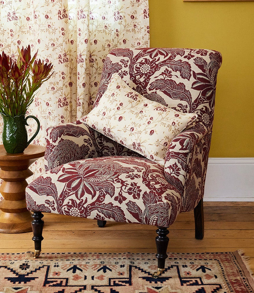 Utopia Goods: cozy living room with floral upholstered chair, patterned curtains, yellow walls, and decorative rug
