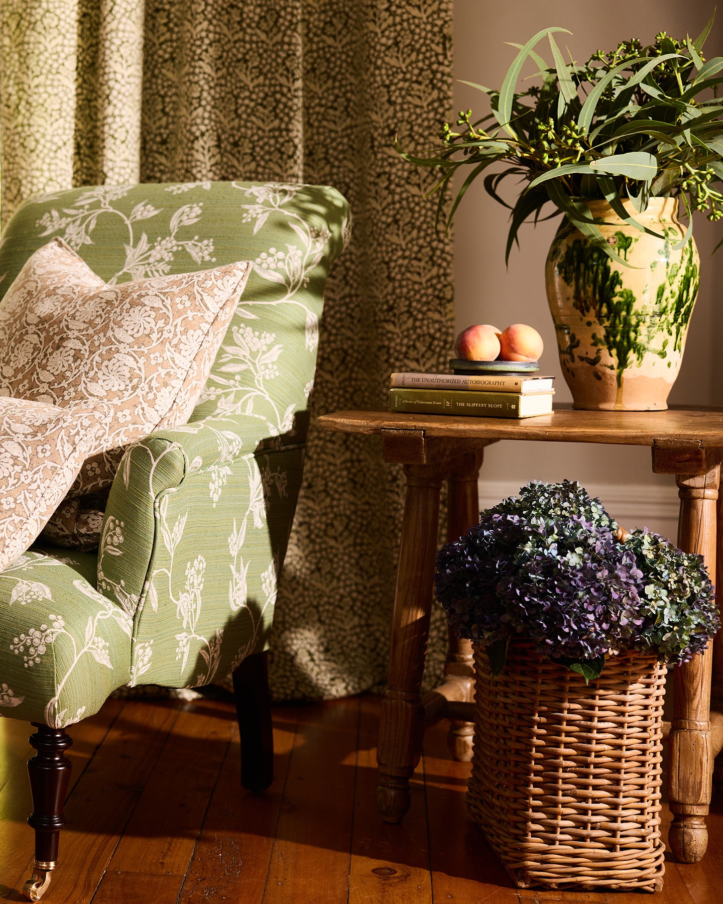 Utopia Goods: cozy living room with green floral armchair, wooden side table, decorative vase, and wicker basket