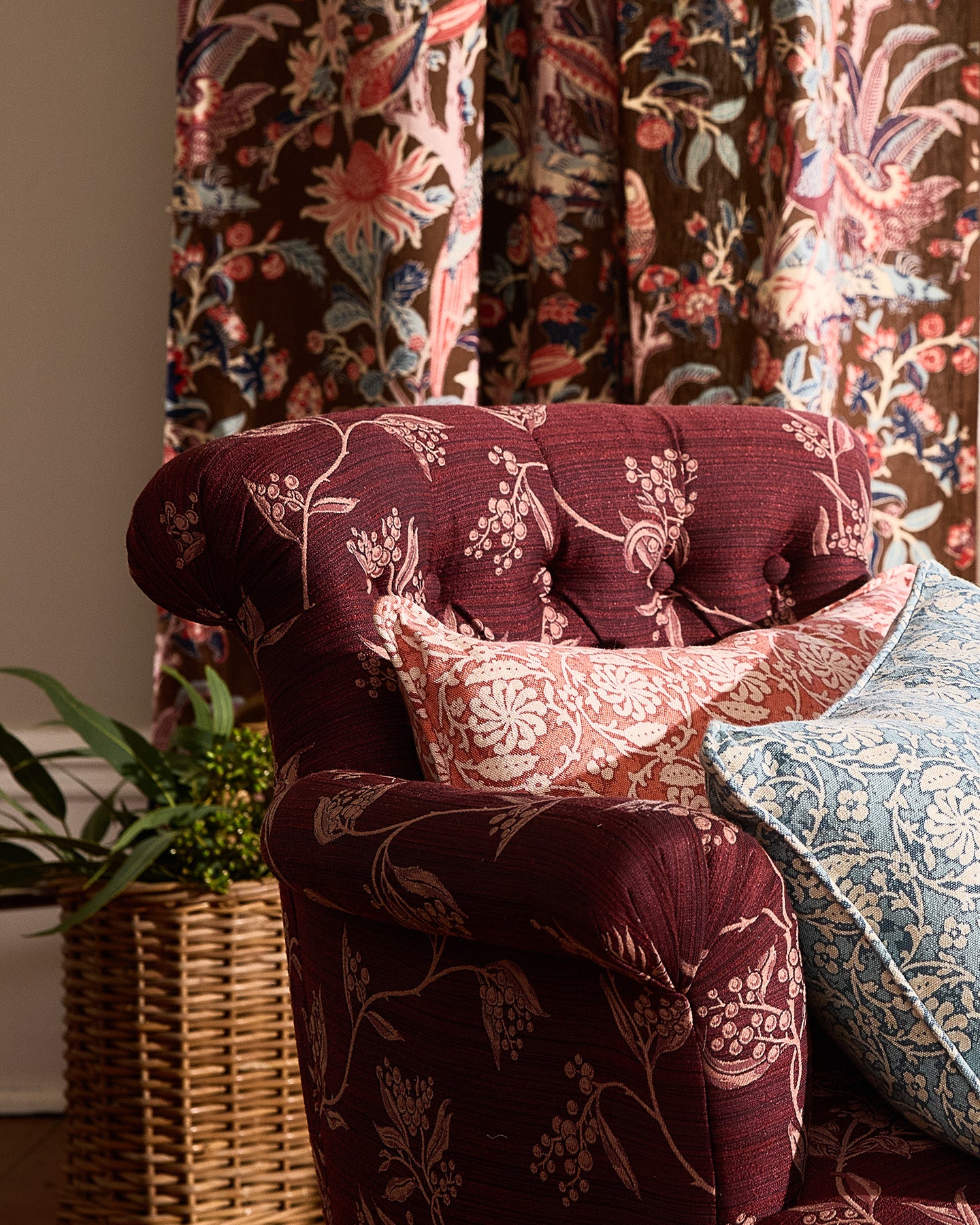 Utopia Goods: burgundy upholstered armchair with floral pattern, decorative pillows, and matching curtains in background